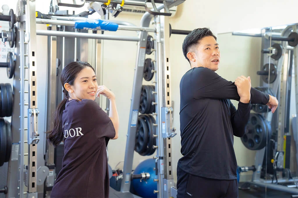 早田トレーナーと女性が準備体操をしている。